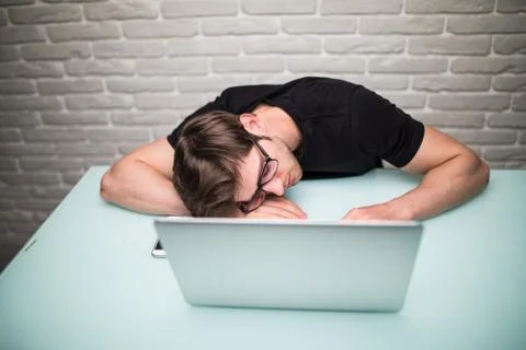 Young handsome man with computer in the office thinking over task in programm Foto stock