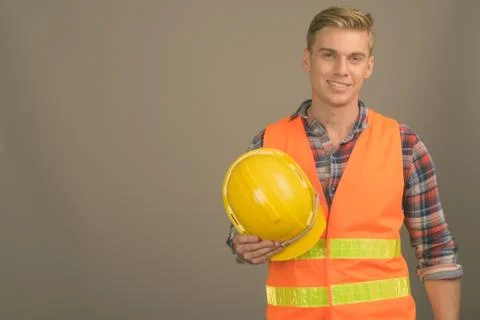 Young handsome man construction worker with blond hair against gray background Foto stock