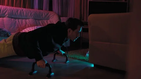 A young handsome man is doing push-UPS in a room and doing sports Stock Footage 128462125
