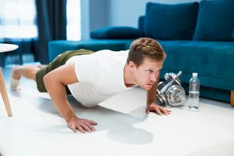 Young handsome man doing pushups on the floor during workout at home sporty and Stock Photos
