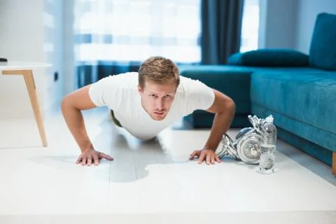 Young handsome man doing pushups during workout at home looking focused sporty Stock-Fotos