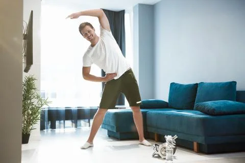 Young handsome man doing sideways during warm up before workout at home looking Foto stock