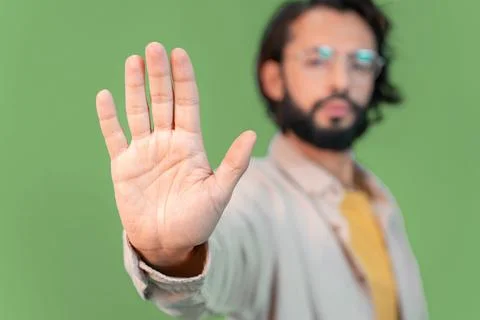 Young handsome man doing stop sing with palm of the hand standing over green Stock Photos
