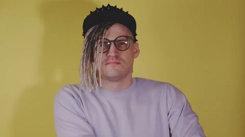 Young handsome man with dreadlocks in black cap, glasses preening himself in Stock Footage 199473714