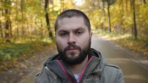 Young handsome man dressed in a jacket walking in a autumn forest. Portrait on Stock Footage 82606052