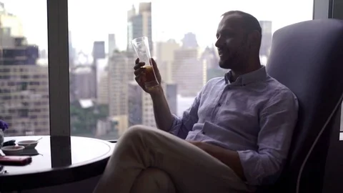 Young handsome man drinking beer in cafe close to the window with city view, 4K Stock Footage 72440935