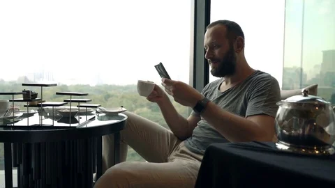 Young, handsome man drinking coffee and using smartphone in cafe, 4K Stock Footage 74209085