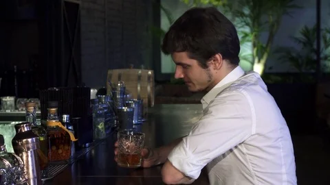 Young handsome man drinking whiskey at the bar alone smiling cheerfully to the Stock Footage 84685564