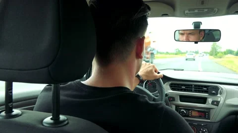 Young handsome man drives a car on the road in the countryside Stock Footage