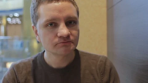 Young handsome man eating tasty hamburger and drinking soda at food court Stock Footage 74434412