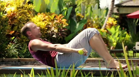 Young, handsome man exercising sit-ups in the garden HD 動画素材 39969799