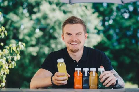 Young handsome man with fresh detox juice in plastic bottles. Organic vegetable Stock Photos