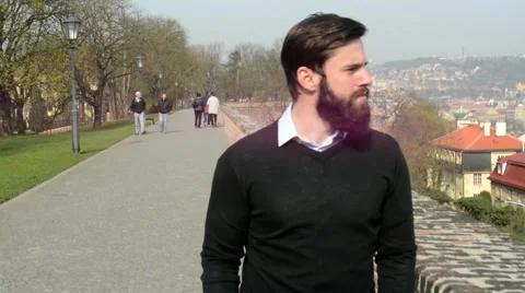 Young handsome man with full-beard (hipster) walking in park and looks on city Stock-Footage 49763383