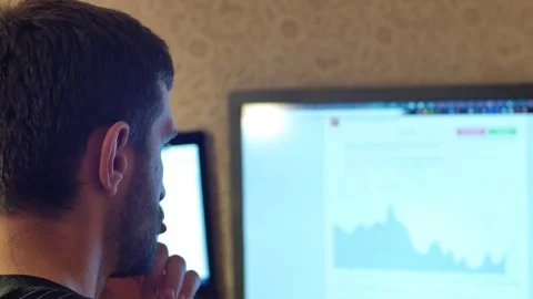 Young handsome man with full-beard hipster works on desktop computer at home or Vidéo 72474298