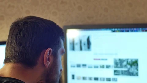 Young handsome man with full-beard works on desktop computer at home or in the Stock Footage 72518608