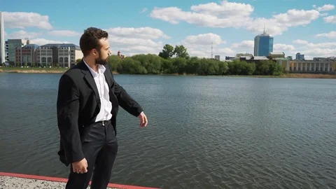 Young handsome man with full-beard hipster talks to camera - city in background Видео 75969434
