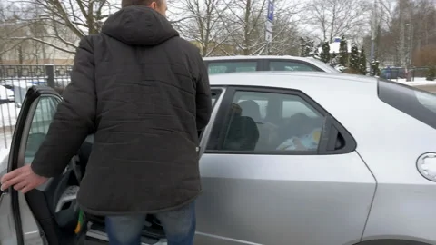 Young handsome man getting into a car and waving his hand in winter Stock-Footage 92934907
