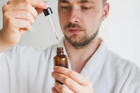 Young handsome man going to apply skin care product on his face. Stock Photos