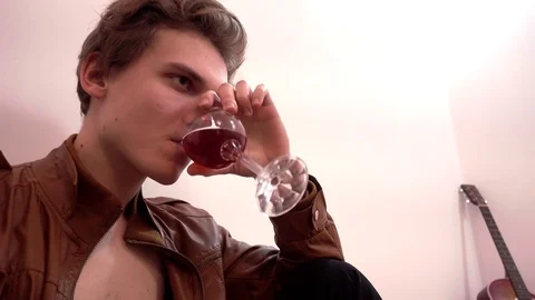 Young, Handsome Man Guy alone Drinking Beverage Wine sitting in ampty room Stock Footage 71578470