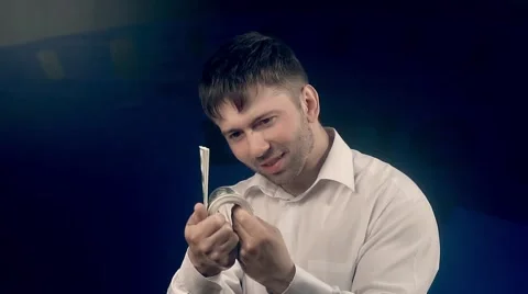 Young handsome man holding a bundle of money counts his dollars Stock-Footage 68566076