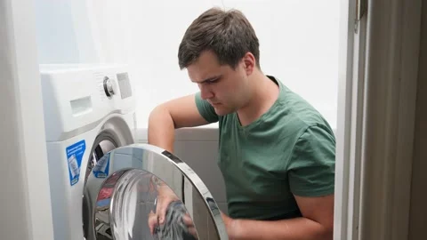 Young handsome man loading dirty clothes in washing machine and doing laundry Video stock 146203688