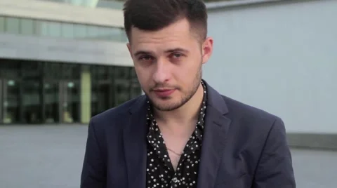 Young, handsome man looking at the camera. Businessman standing on the street Stock Footage 54685244