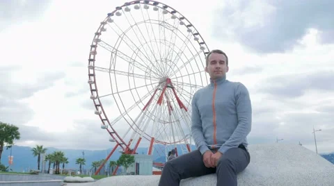Young handsome man looking into the camera and smiles around the Ferris wheel Video stock 67611541