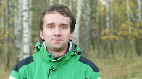 Young handsome man looking into the camera in autumn park. Equip a green sports Stock Footage 68575554