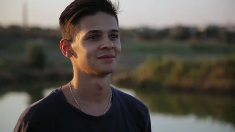 Young handsome man looking at camera near the pond at sunset  3 Видео 94442412