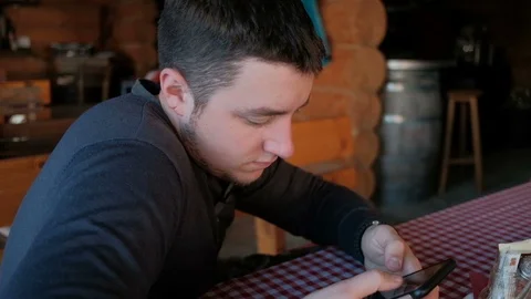 Young handsome man looking at cell phone in a cafe or restaurant. Video stock 88616033