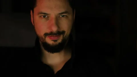 Young handsome man makes playfull, sly, nasty, smile to the camera. Color light Stock Footage 169239458