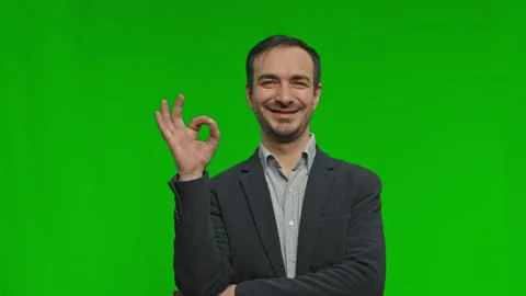 Young handsome man making OK sign over green background and smiles to camera. Stock Footage 172093865