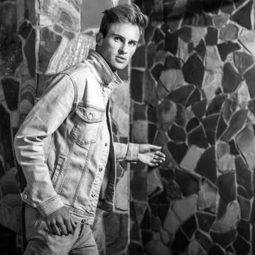 Young handsome man model against natural stone background. Black-white portrait. Stock Photos