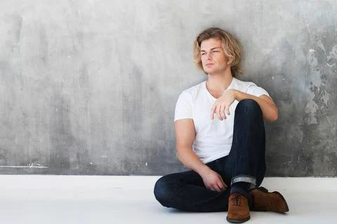 Young handsome man model sitting on the floor. Studio fashion portrait Stock-Fotos