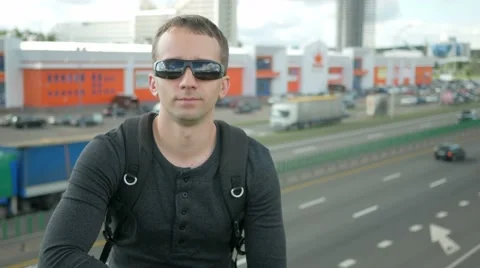 Young handsome man in a nice fitting clothes removes and wears sunglasses. urban Stock Footage 66577505