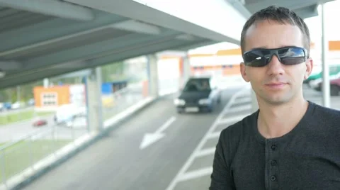 Young handsome man in a nice fitting clothes removes and wears sunglasses and Stock Footage 66578328