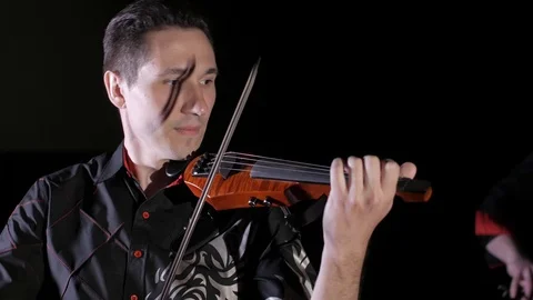 Young handsome man plays electric violin on black background, isolated Stock-Footage 107871376