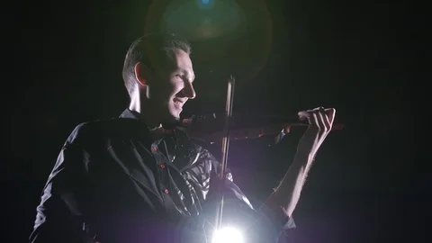 Young handsome man plays electric violin on black background, isolated Stock Footage 107871585