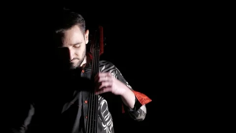 Young handsome man plays electric cello on black background, isolated Stock-Footage 107871823