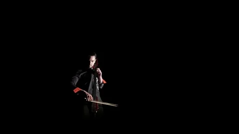Young handsome man plays electric cello on black background, isolated Stock Footage 107871848