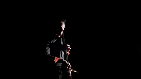 Young handsome man plays electric cello on black background, isolated Vídeos de archivo 107871857