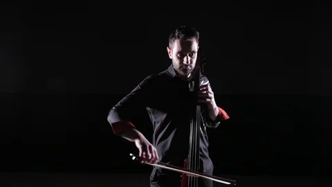 Young handsome man plays electric cello on black background, isolated Stock Footage 107871987