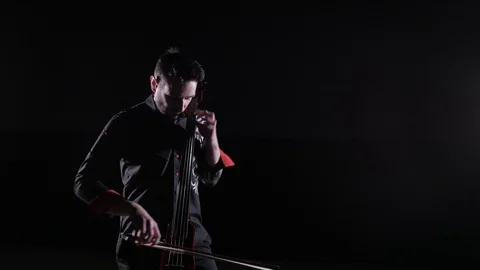 Young handsome man plays electric cello on black background, isolated Stock-Footage 107872007