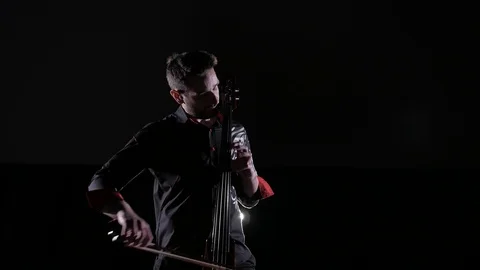 Young handsome man plays electric cello on black background, isolated Stock Footage 107872047