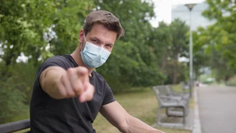 A young handsome man points at the camera and nods as he sits on a bench in a Stock-Footage 145195780