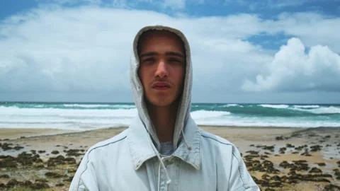 Young handsome man is  posing against blue sea with clouds on the sky. Stock Footage 204693805