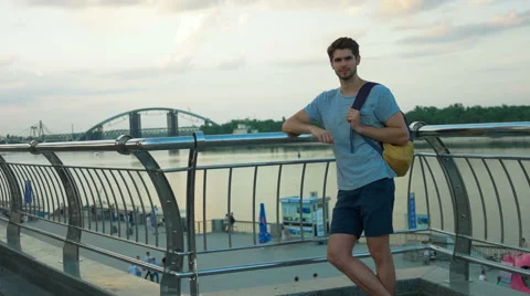 Young handsome man posing on a camera in front of a river Stock Footage 68599357