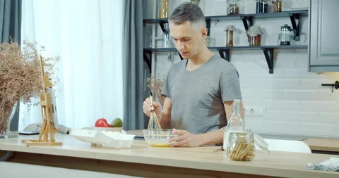 Young handsome man preparing dough for cookies using a tablet for tips Video stock 131523810
