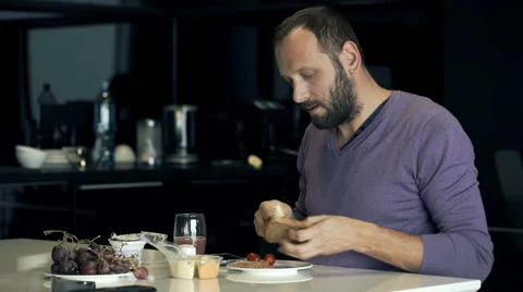 Young, handsome man preparing sandwich during breakfast in the kitchen Stock Footage 66767047