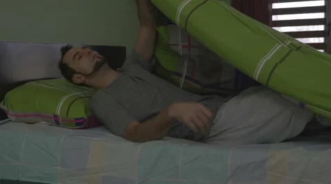 Young handsome man pulling the blanket and going to sleep Stock Footage 59841181